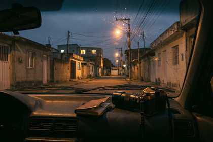 Calle de un pueblo al atardecer vista desde un auto estacionado, con una cámara sobre el tablero